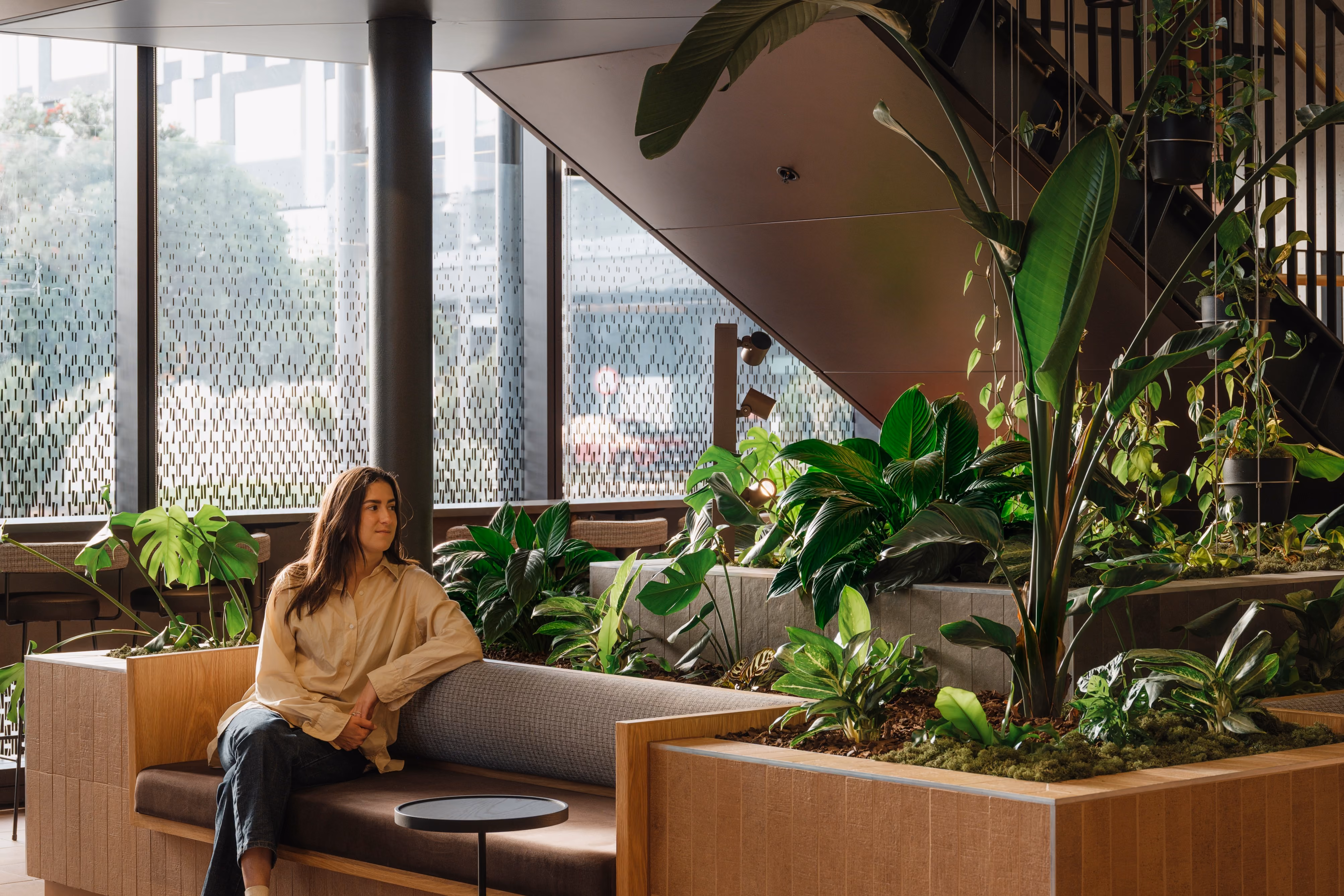 Built-in bench beside a dense under-stair planter of Strelizia, Monstera and Calathea.