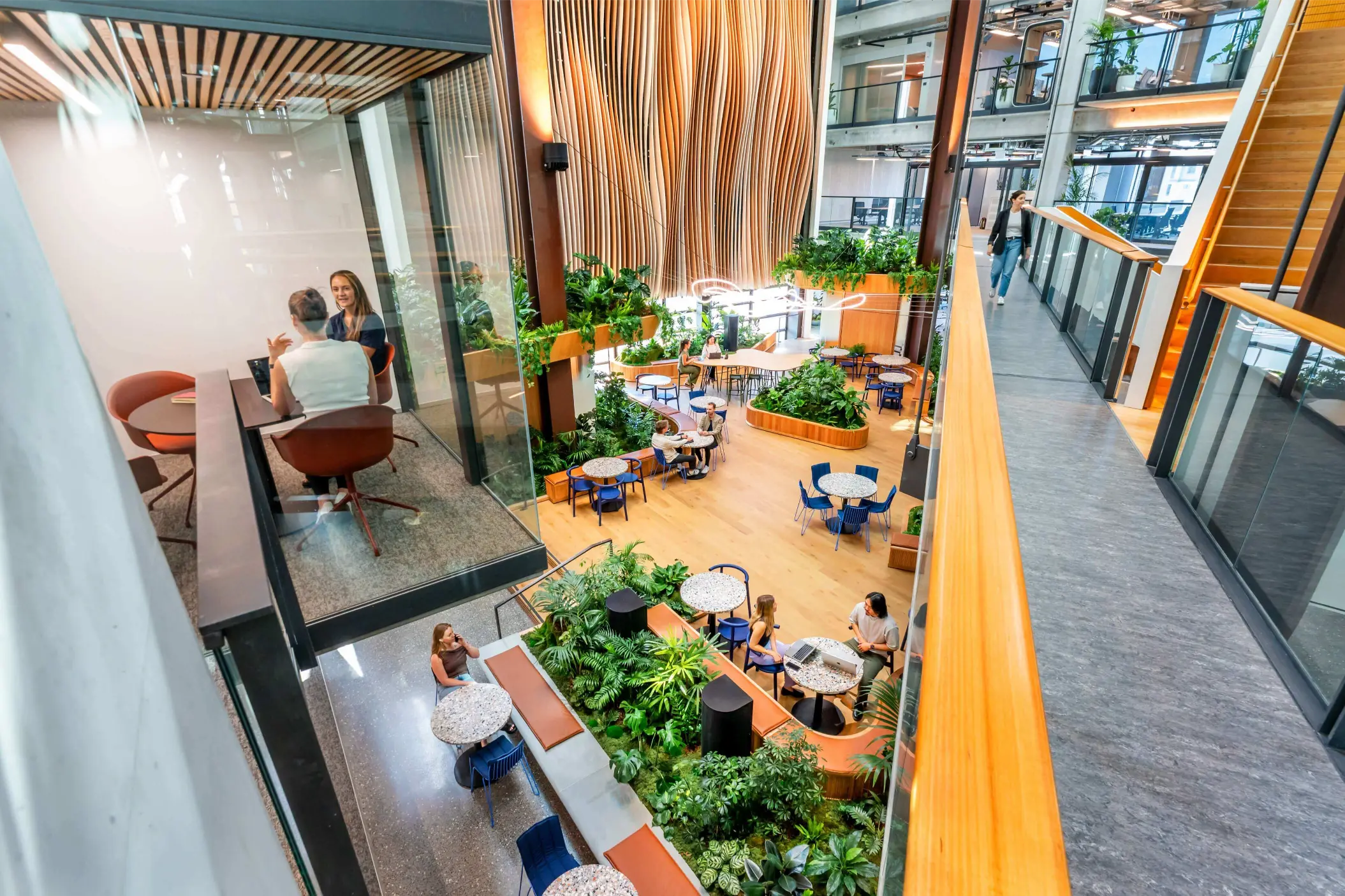 Lush multi-level planting integrated through the B:HIVE+ coworking atrium, with greenery framing seating areas and timber planters