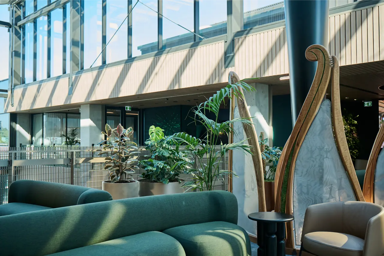 Floorstanding planters in tucked behind green couches and beside a glass balustrade.