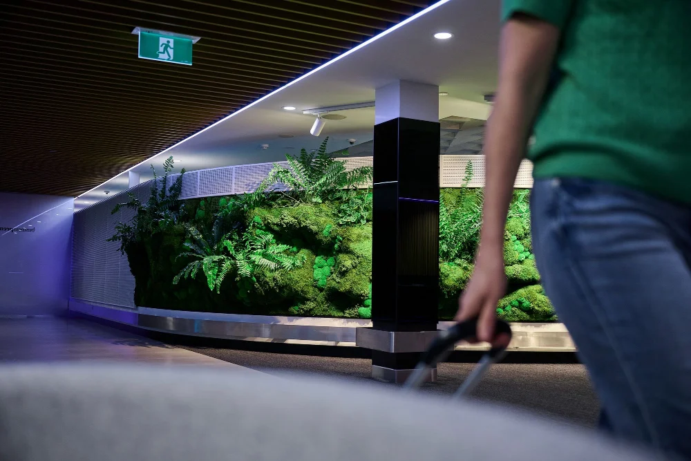 A traveller with luggage walking past the Forest Wall in the check-in hall.