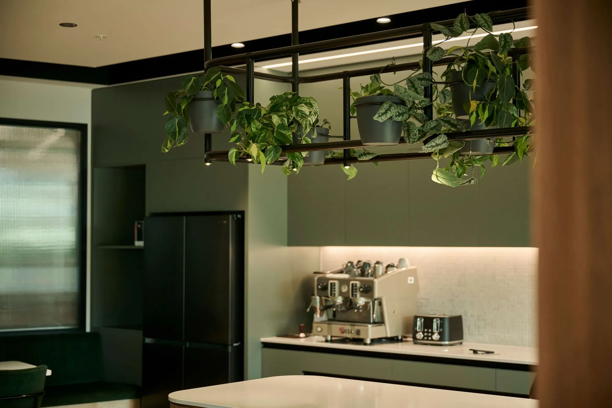 Custom hanging planter rack with trailing pothos above the kitchen island and coffee station.