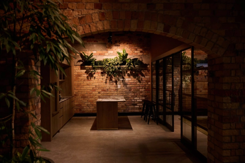 Arched brick room at Gold Merchants with a spotlit wall planter of greenery