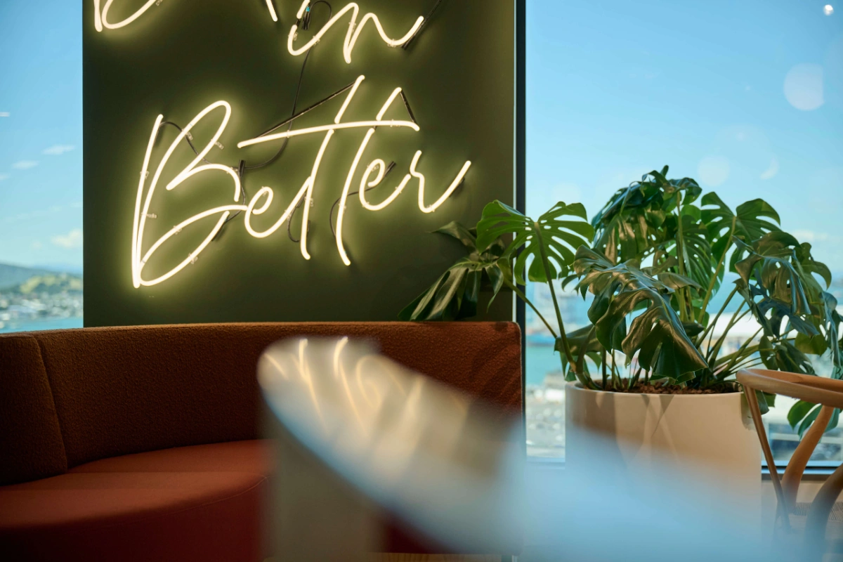 Monstera in a white planter beside the Believe in Better neon sign at Oceania