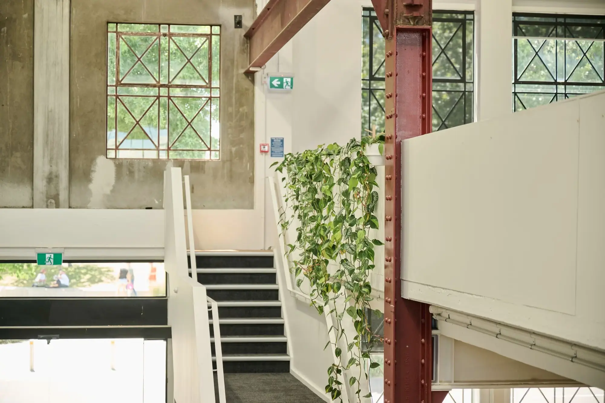 Pothos cascading beside a stairwell with exposed steel and industrial windows at Partly