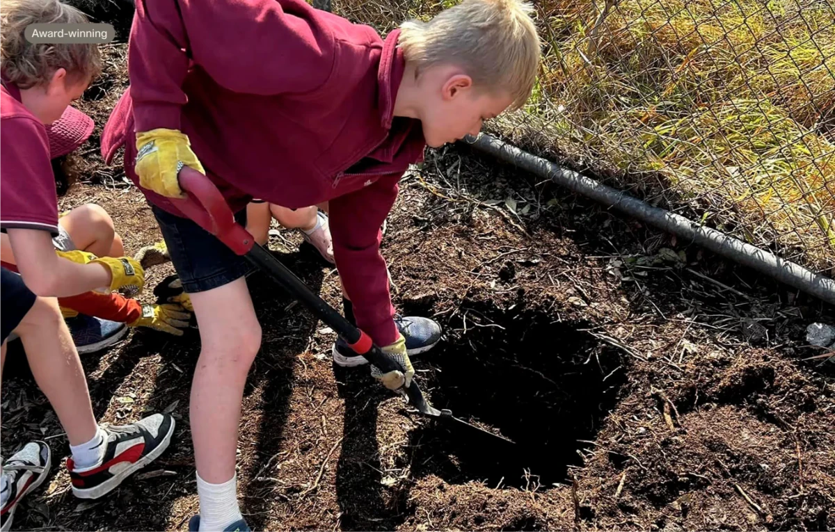 Students digging compost into the soil in the Sylvia Park community garden