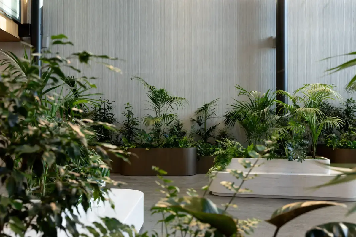 Planters of palms and tropical plants viewed through foreground foliage in the atrium