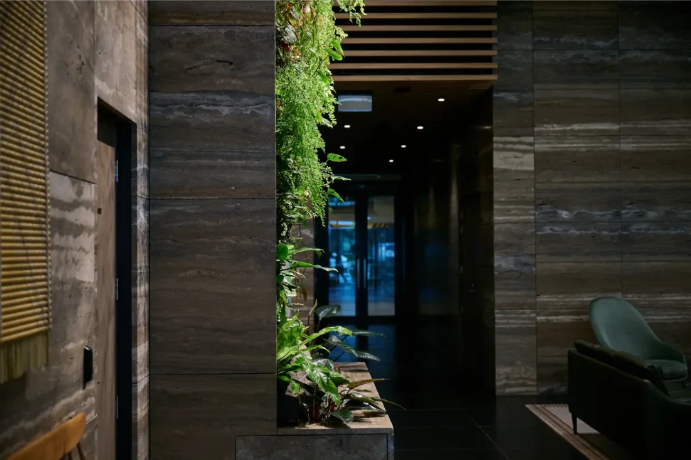 Stone-clad lobby corridor with trailing plants and a low travertine planter