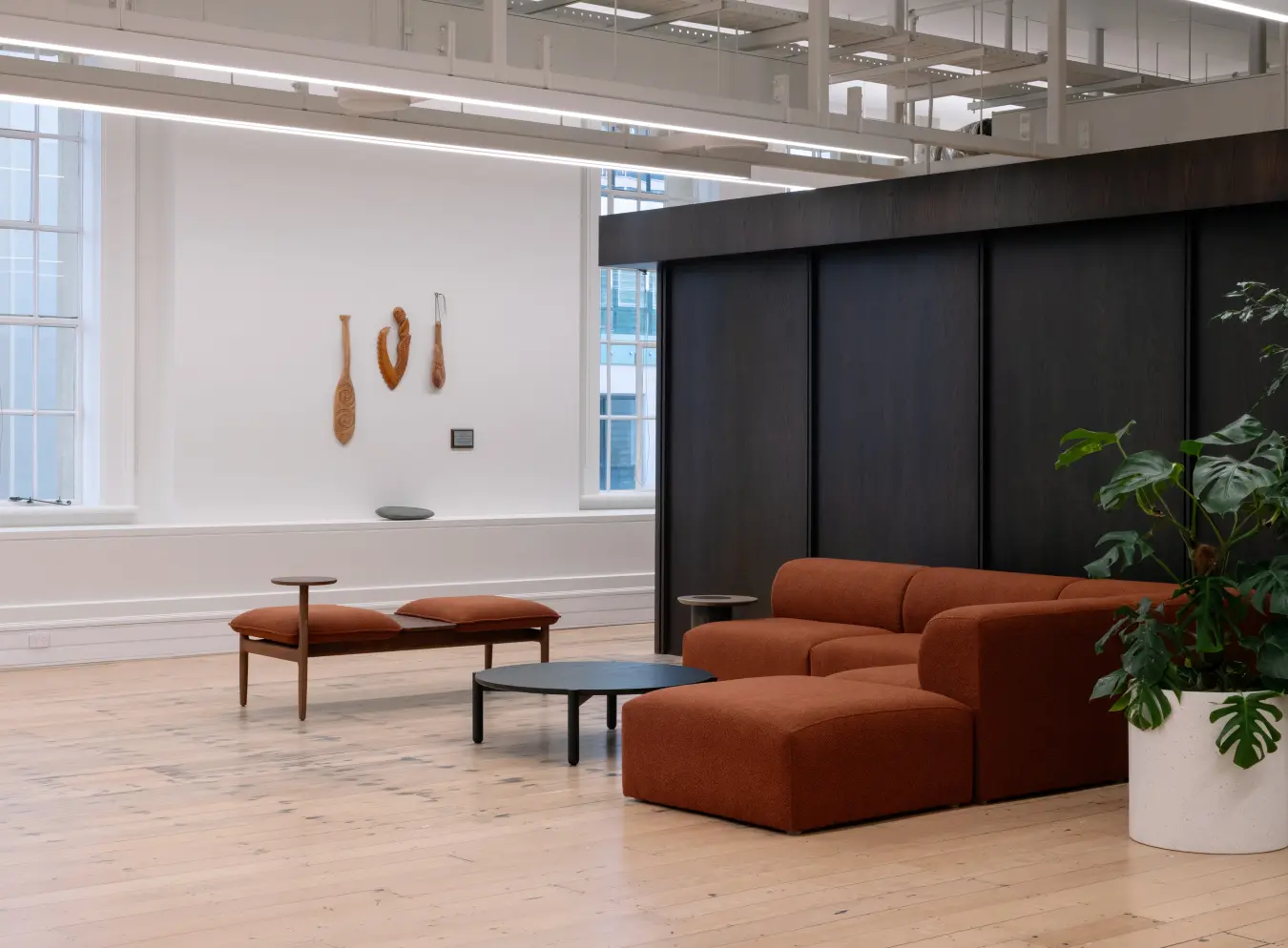 wide shot, rust sofa, minimal greenery visible left side