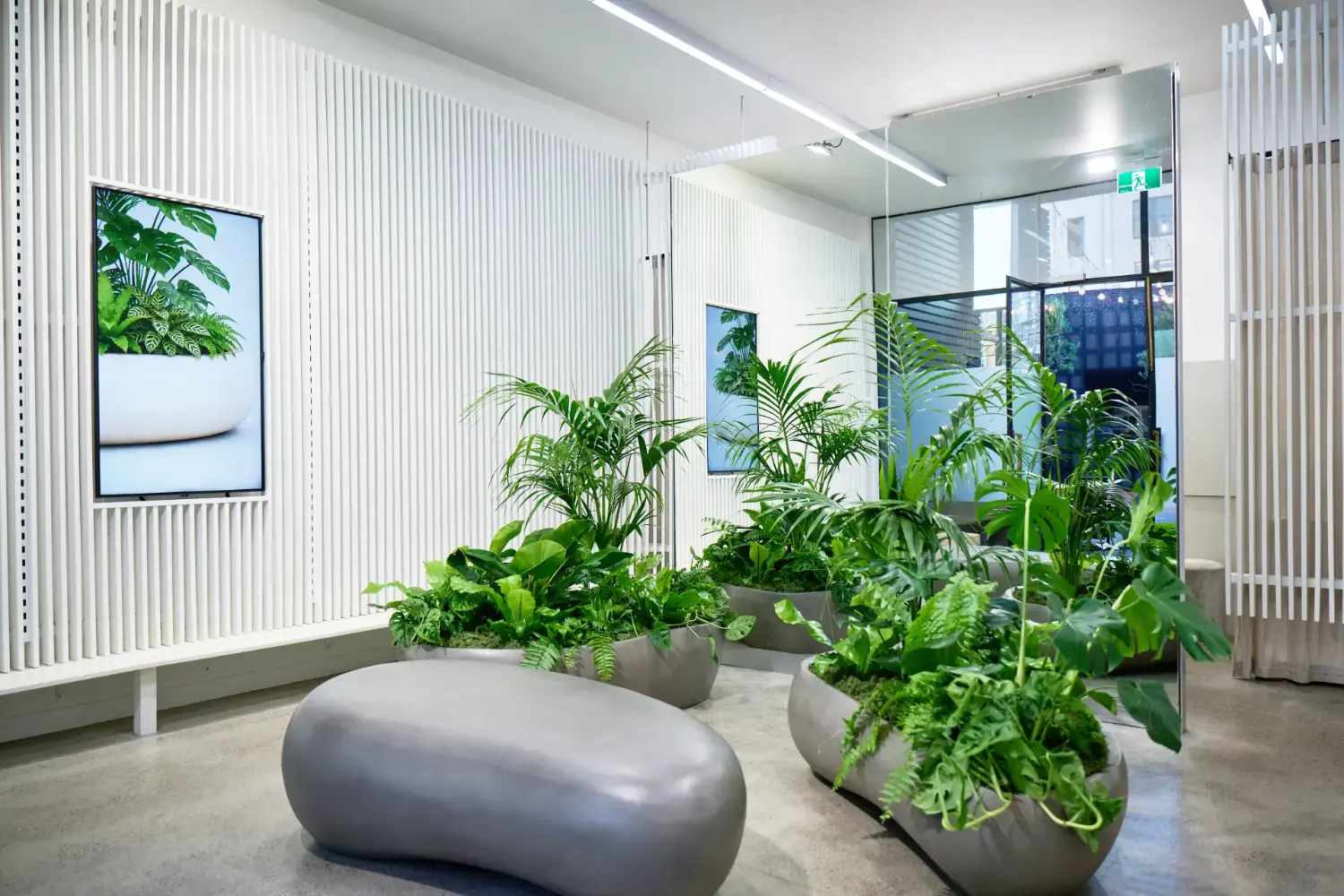 Geode planters with tropical plants in a lobby beside a stone seat