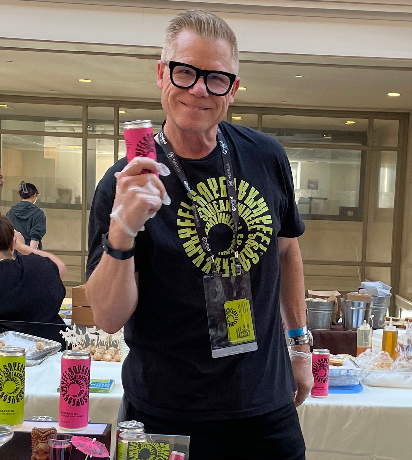 Man smiling at camera holding a beverage can