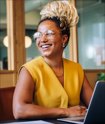 Confident professional woman smiling and working on a laptop in the office