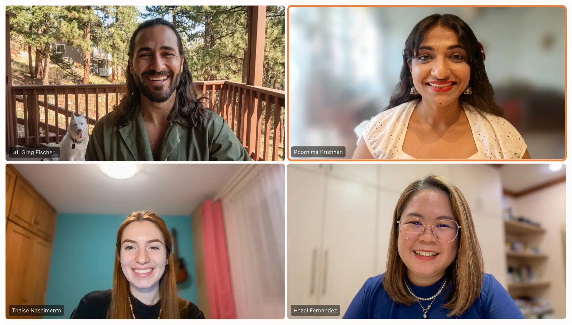 Video call grid with four smiling people: top left is a man with long hair and beard sitting on a wooden balcony with a white dog behind him; top right is a woman with dark hair, wearing a white blouse and earrings; bottom left is a woman with long red hair in a room with blue walls; bottom right is a woman with shoulder-length hair and glasses in a room with shelves, wearing a blue top. Each person is labeled with their names.