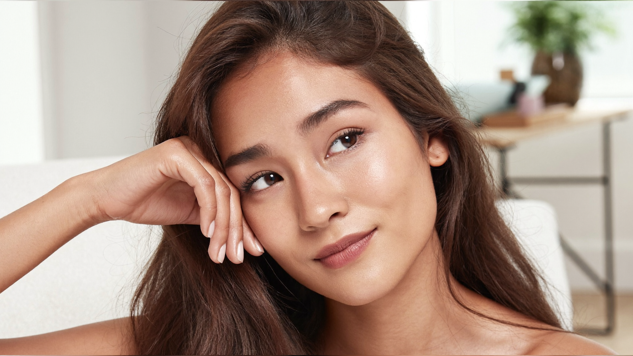 Fresh-faced woman in her late twenties with smooth, dewy natural skin in soft daylight