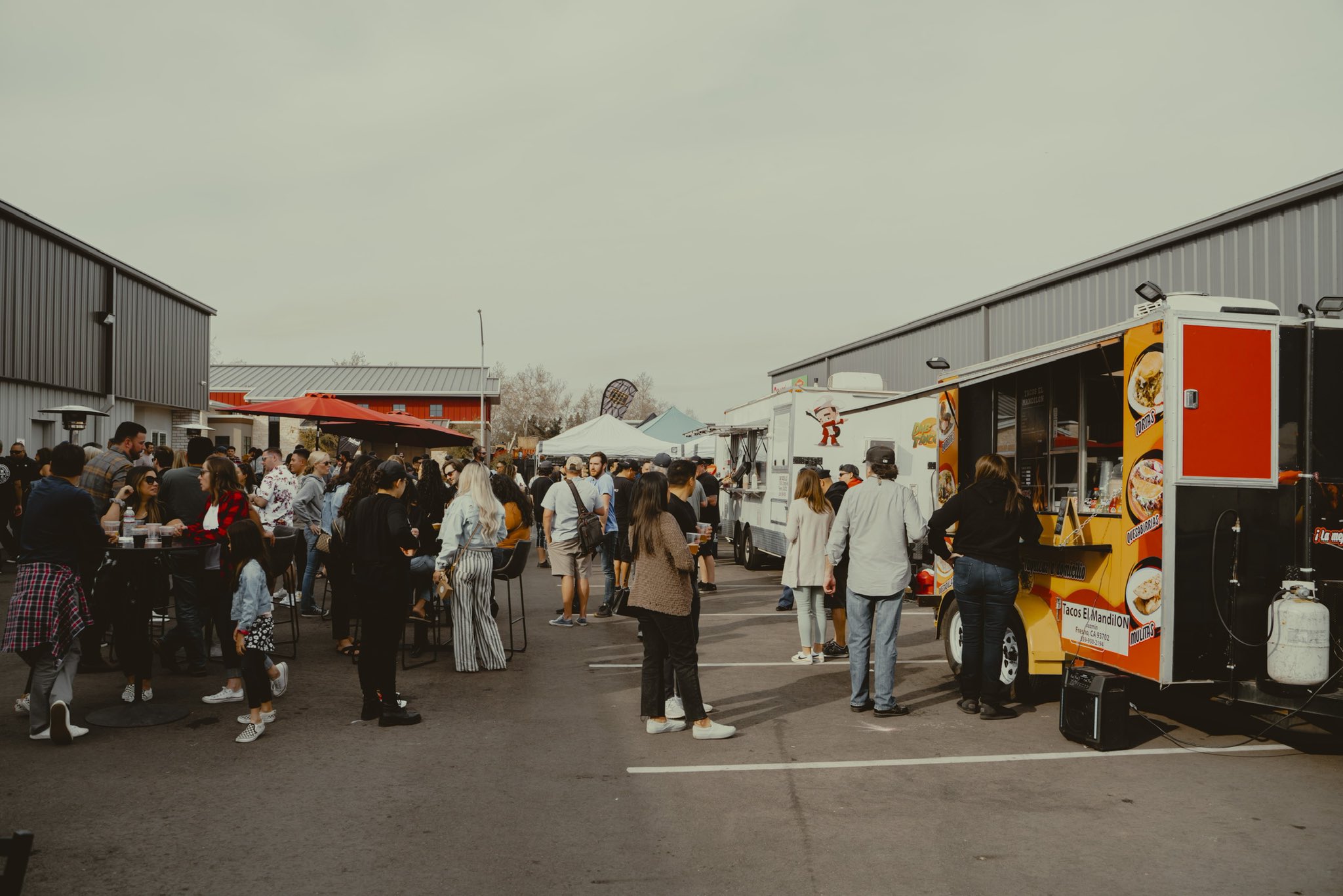 Crowd of people gathered at a street food market with food trucks and outdoor seating.