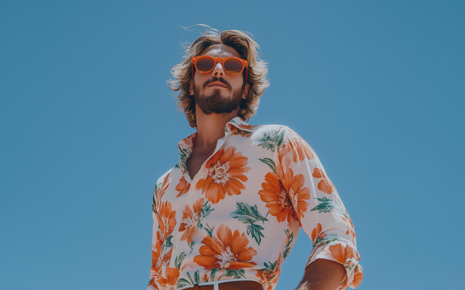Handsome young man in orange classes on clear sky background.