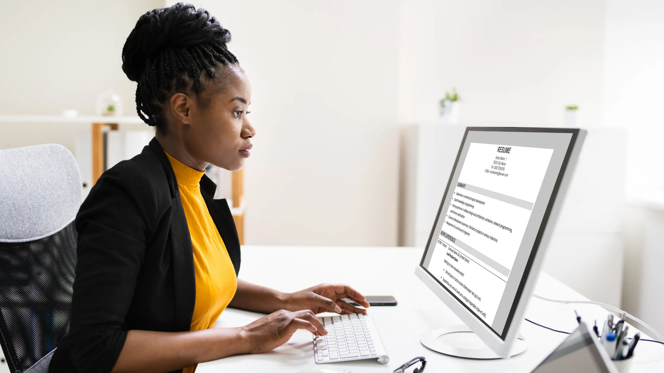 Recruitment specialist reviews resume on desktop computer