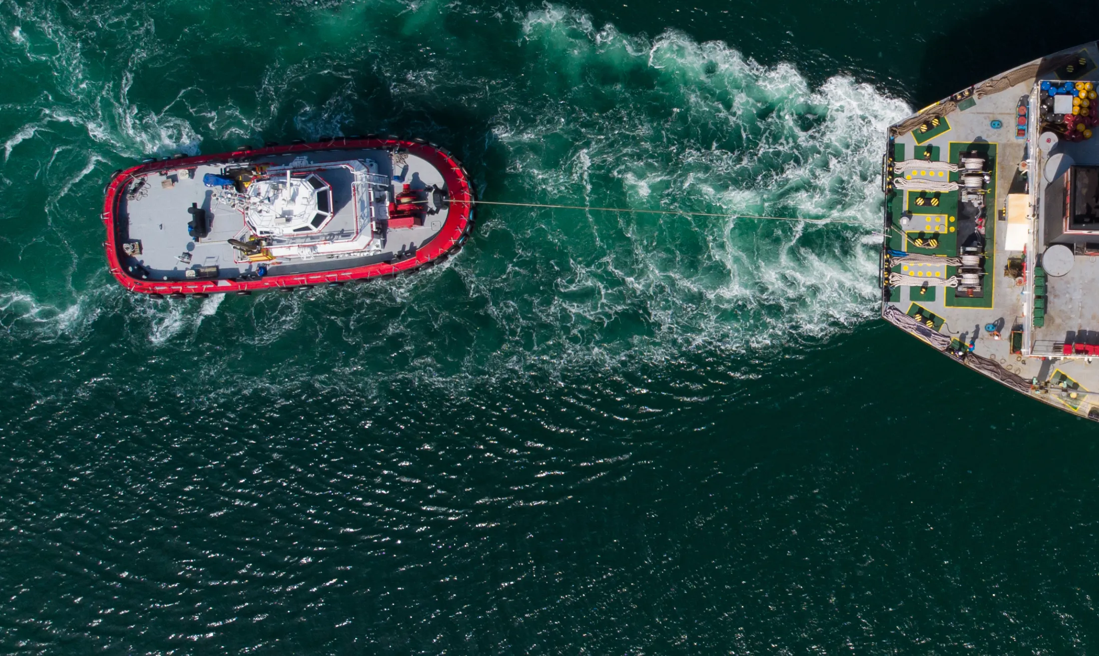 A big ship towing a smaller vessel in the water