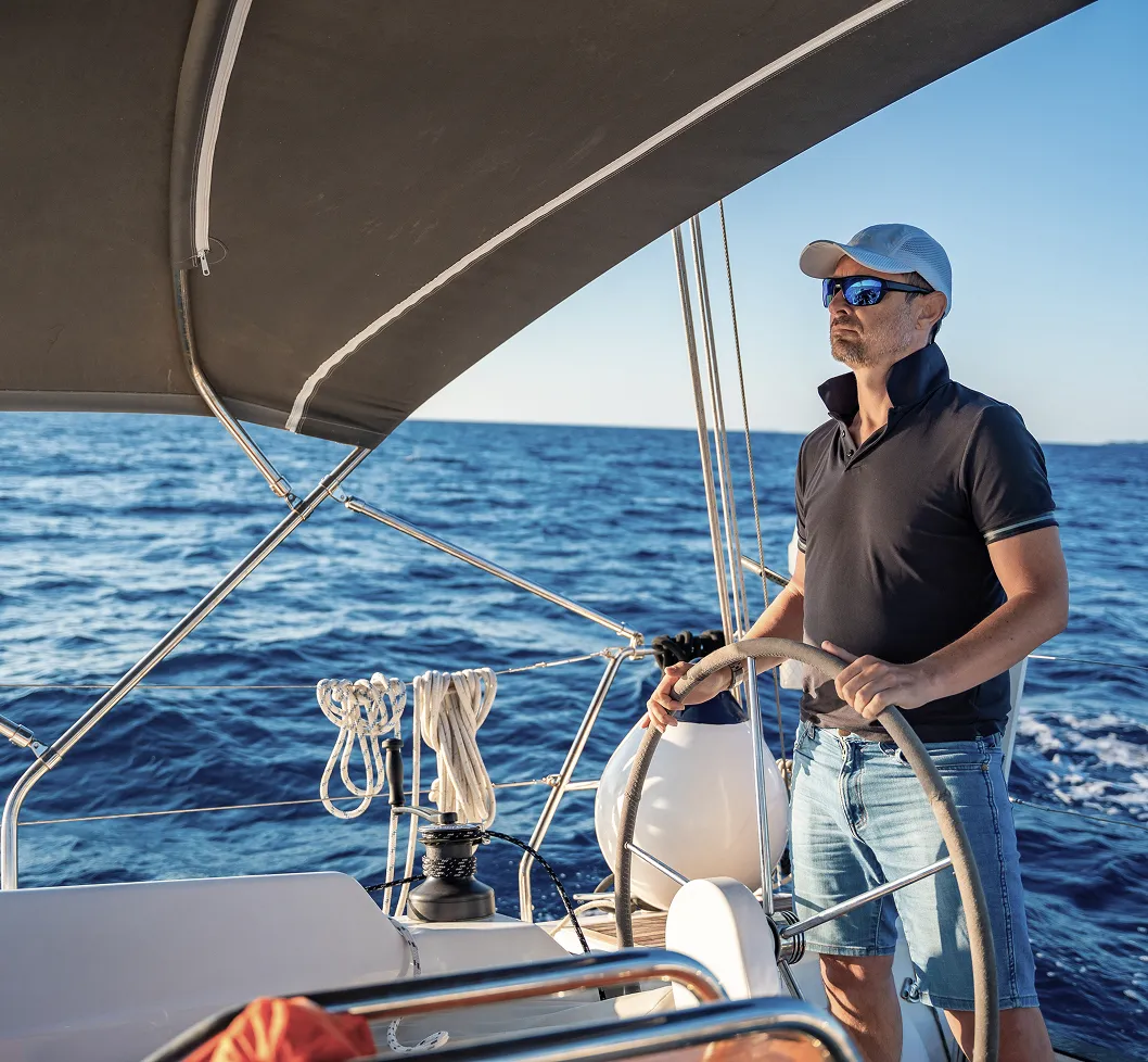 A middle aged male driving the boat and looking at the ocean