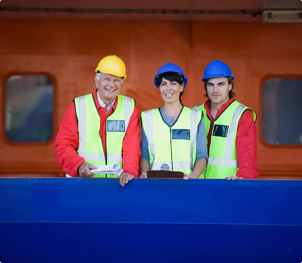 Peopl with safety gear on a ship smilling at the camera