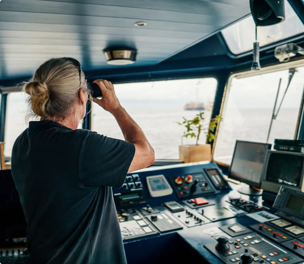 A person in a boat cabin looking at the sea