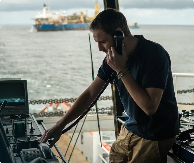 A male in a boat cabin talking on the phone