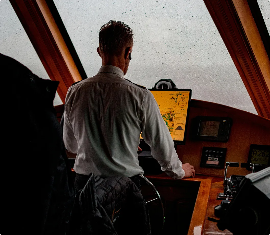 A male in a boat cabin controling it