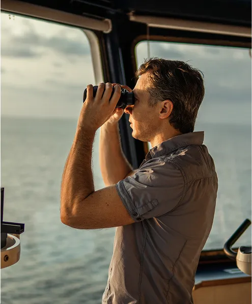 Person in a ship cabin looking at the water