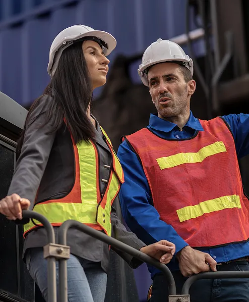 Man and woman in safety gear talking about shipping containers