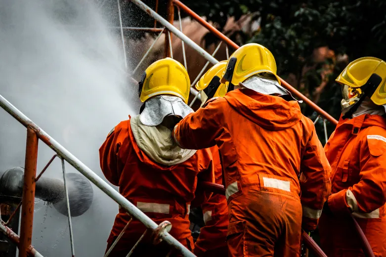Three firefighters in gear spraying water