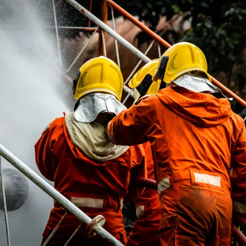 Three people in firefighting gear spraying water