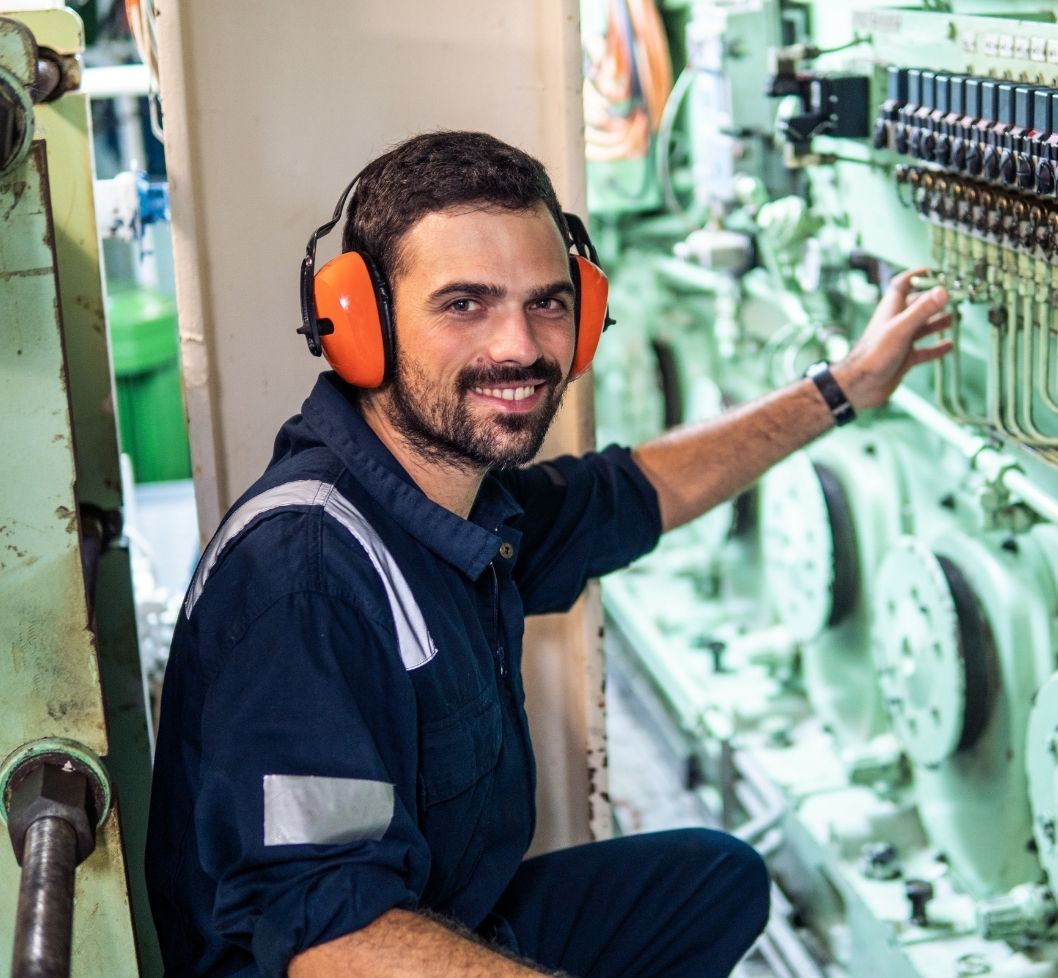 Man with orange headphone in the engine room of a boat