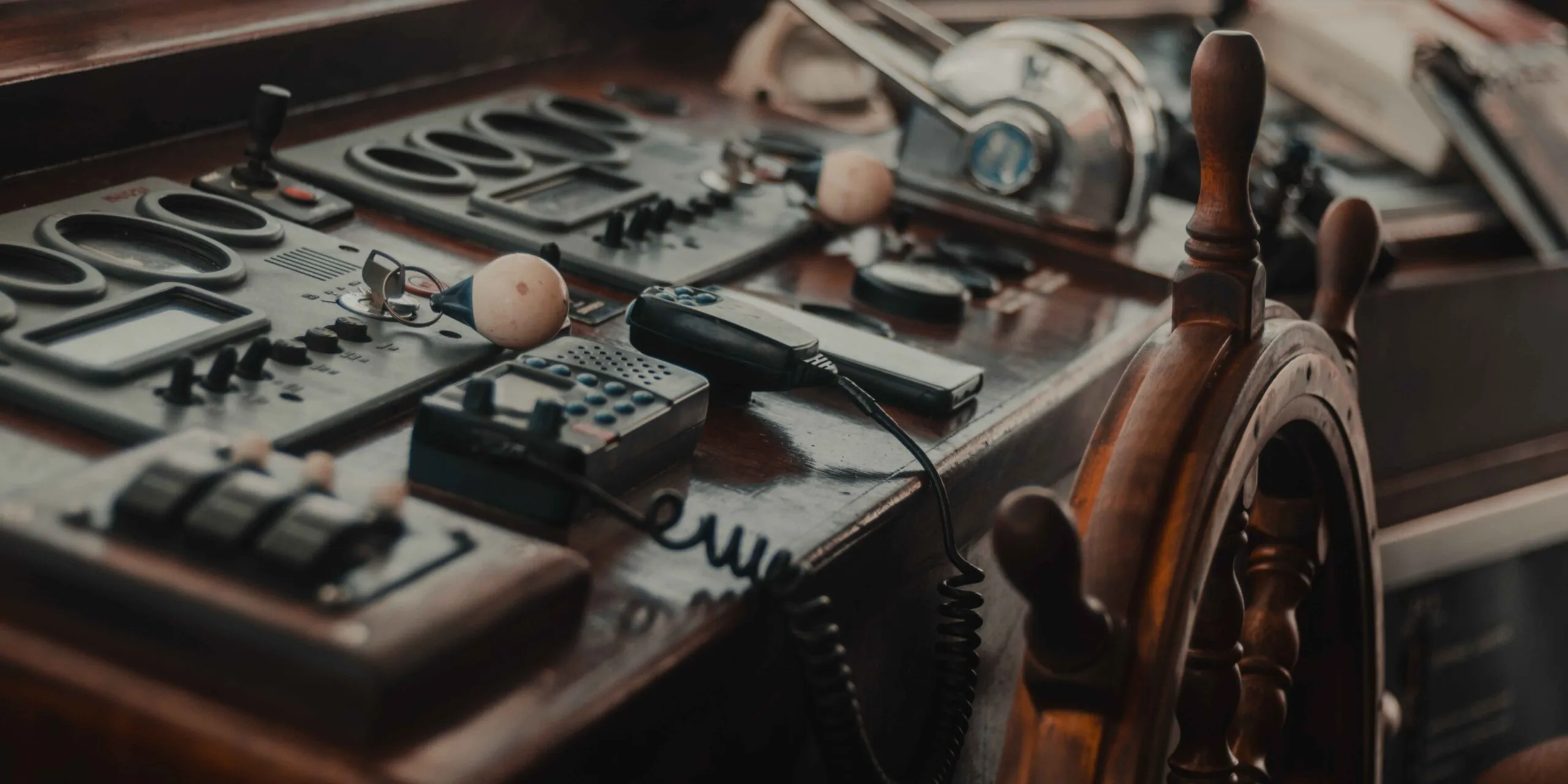 Helm of a boat with a wooden steering wheel.