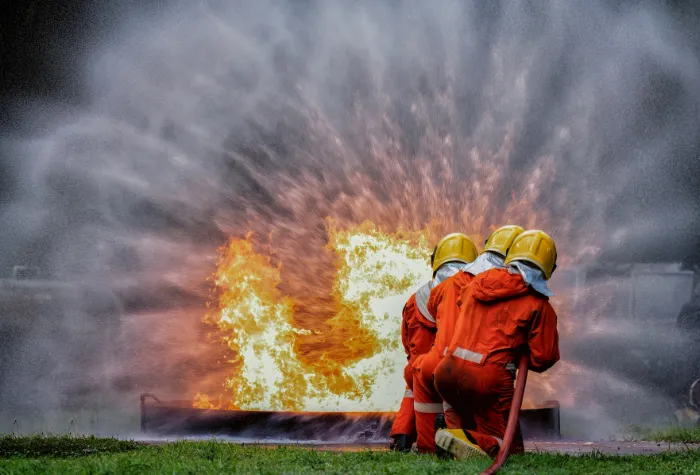 People in fire safety gear putting out small gas fire