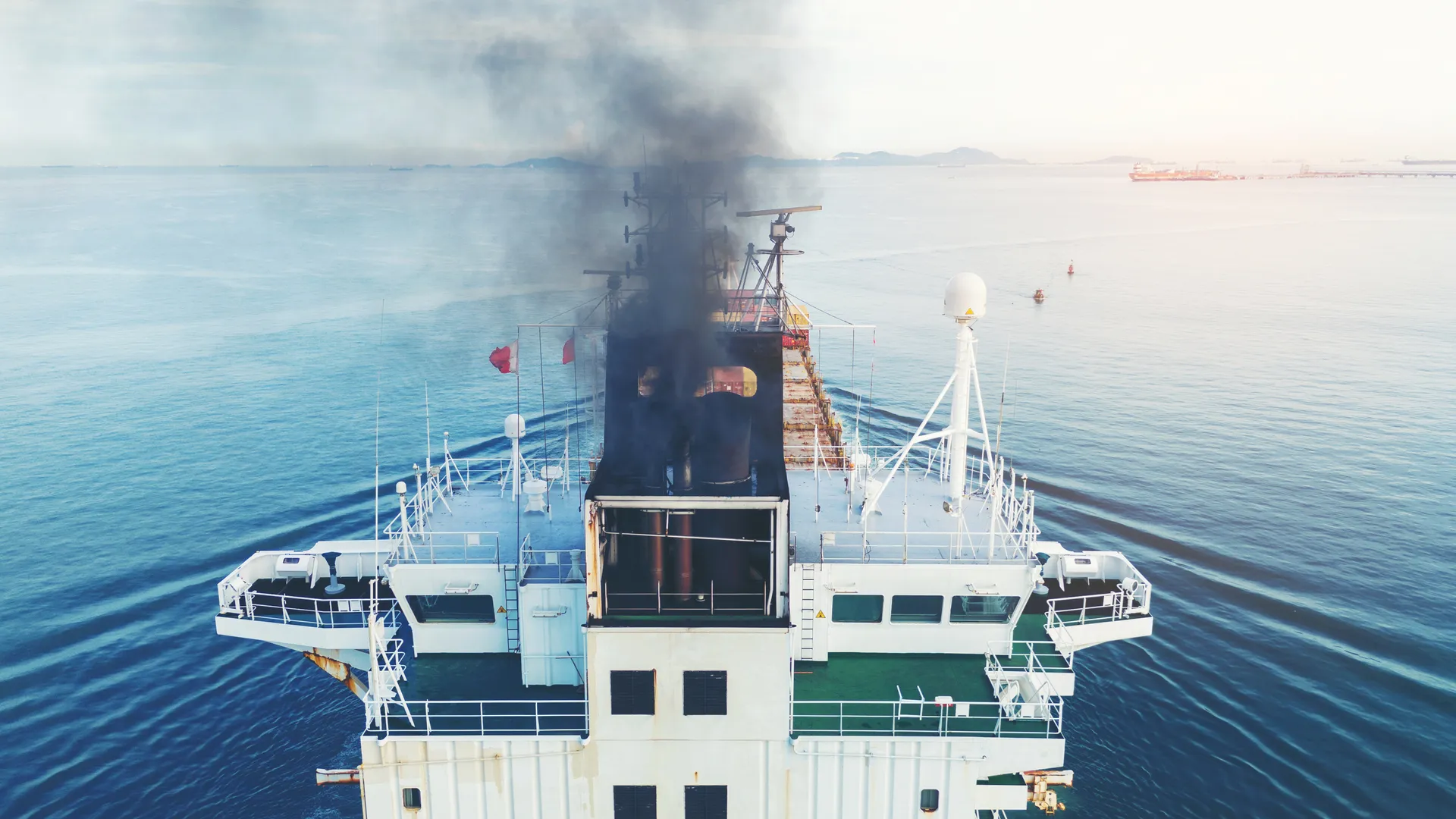 Thick smoke rising from a cargo ship after a fire on boat at sea.