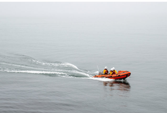 Three lifeguards in a small dingy on the water