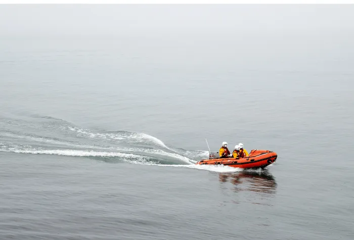 Three lifeguards in a small dingy on the water
