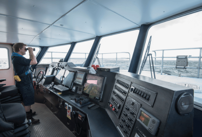 Captain looking through binoculars on the bridge of a ship