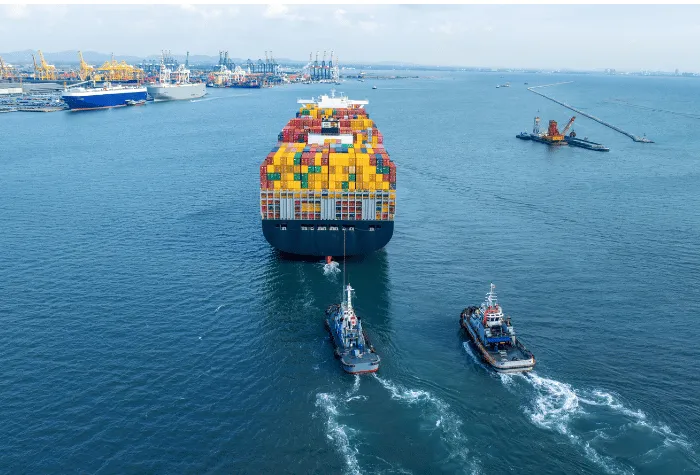 Cargo ship in harbor with two tug boats