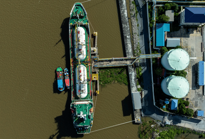 Aerial top view white gas storage tank with LPG tanker ship, LPG distribution station facility