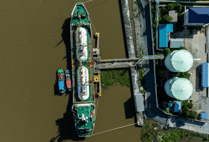 Aerial top view white gas storage tank with LPG tanker ship, LPG distribution station facility