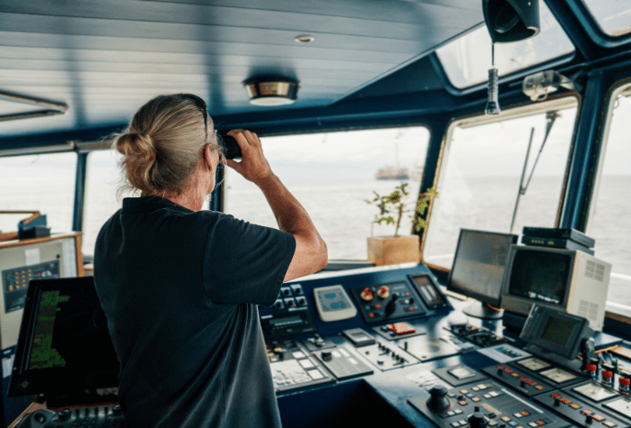 Boat captain looking over the water in the bridge.