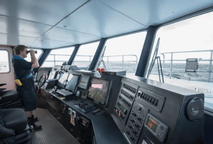 Captain looking through binoculars on the bridge of a ship