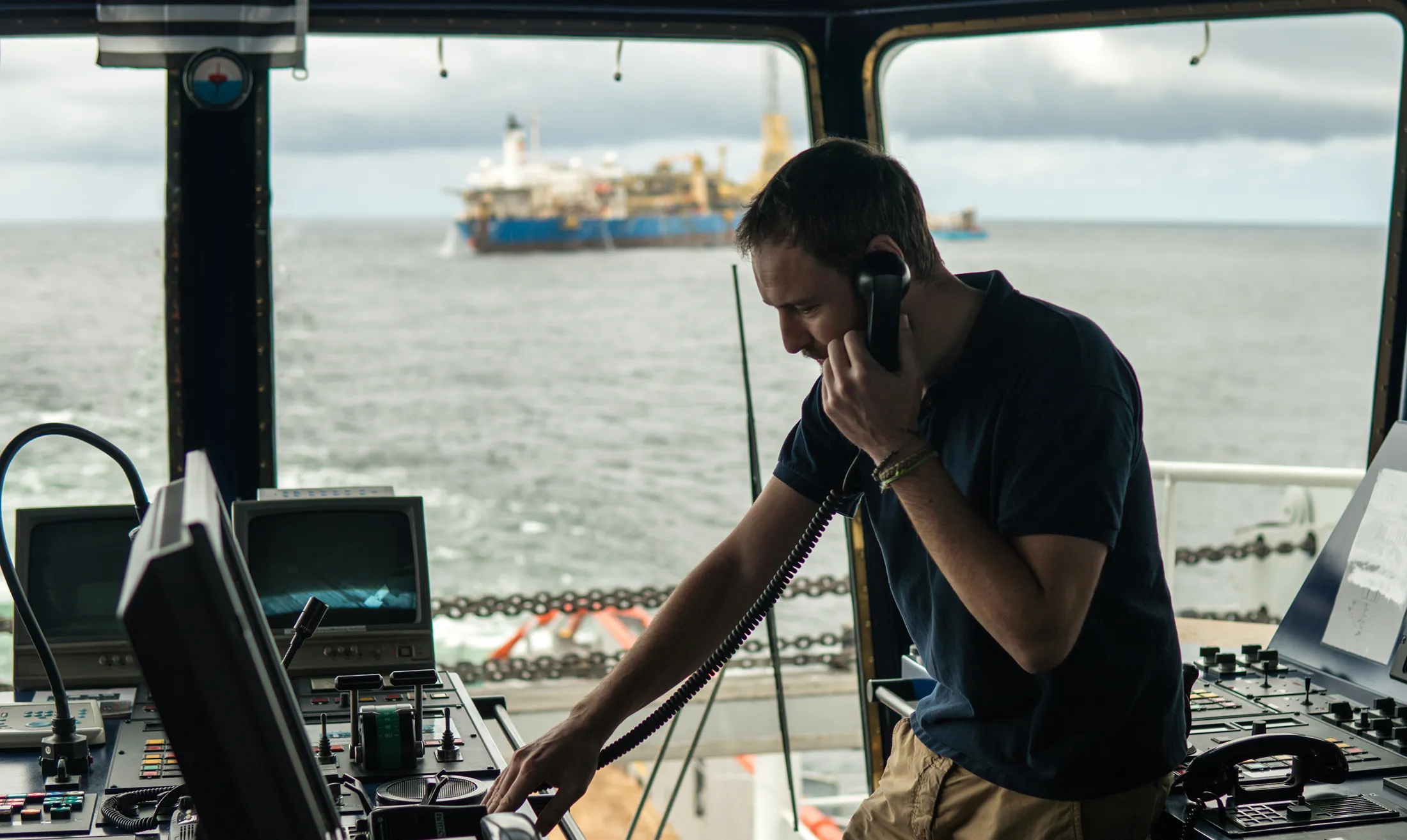 A male in a boat cabin talking on the phone
