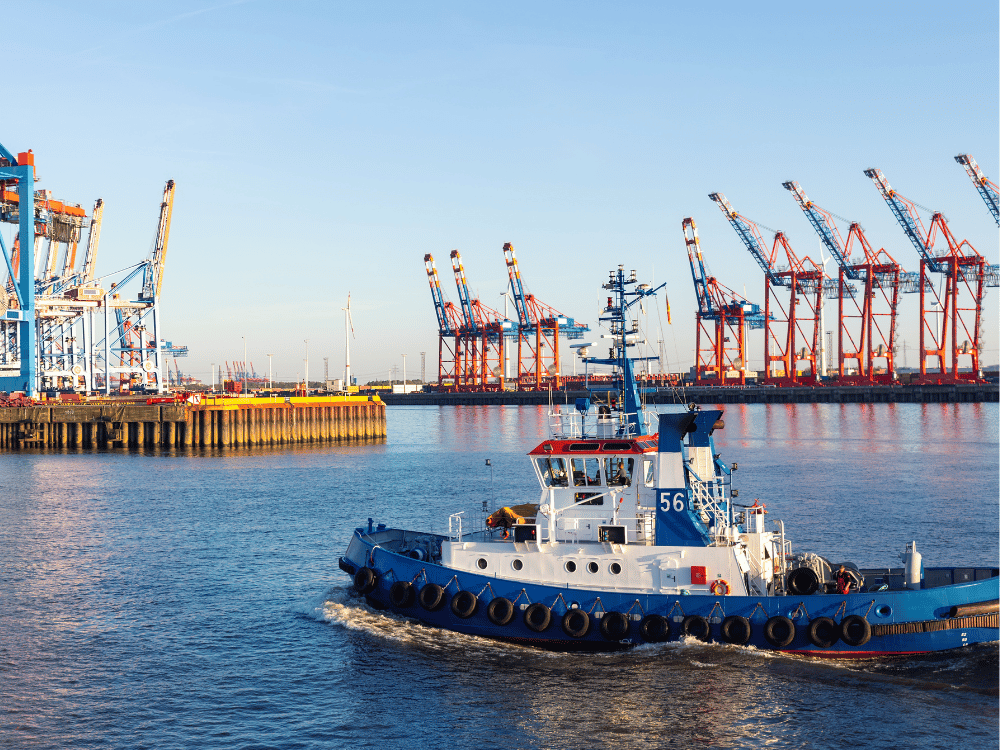 Tug boat in port with cranes in background