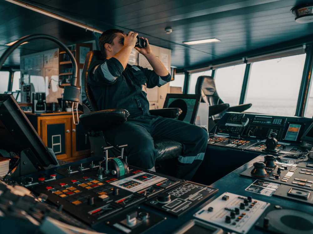 Maritime Captain in bridge looking out over the water with binoculars
