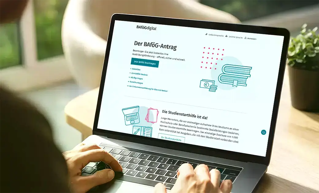 Laptopbildschirm mit geöffneter Webseite zum BAföG-Antrag und Studienstarthilfe, Hände tippen auf Tastatur.