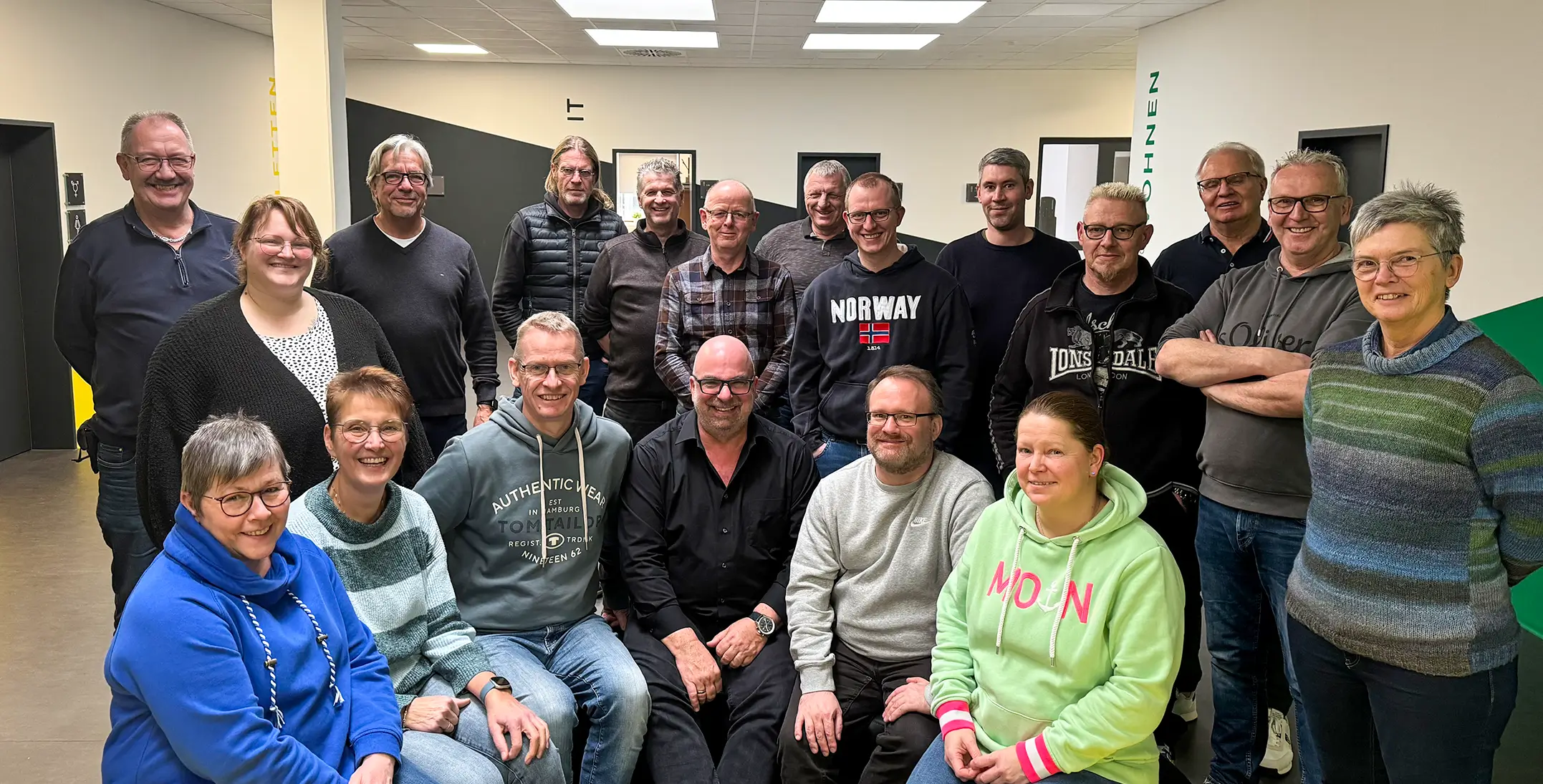 Gruppe von Seminarteilnehmern in einem Raum des Studierendenwerks, einige sitzen auf gelben Sitzbänken, andere stehen dahinter, alle blicken zur Kamera.