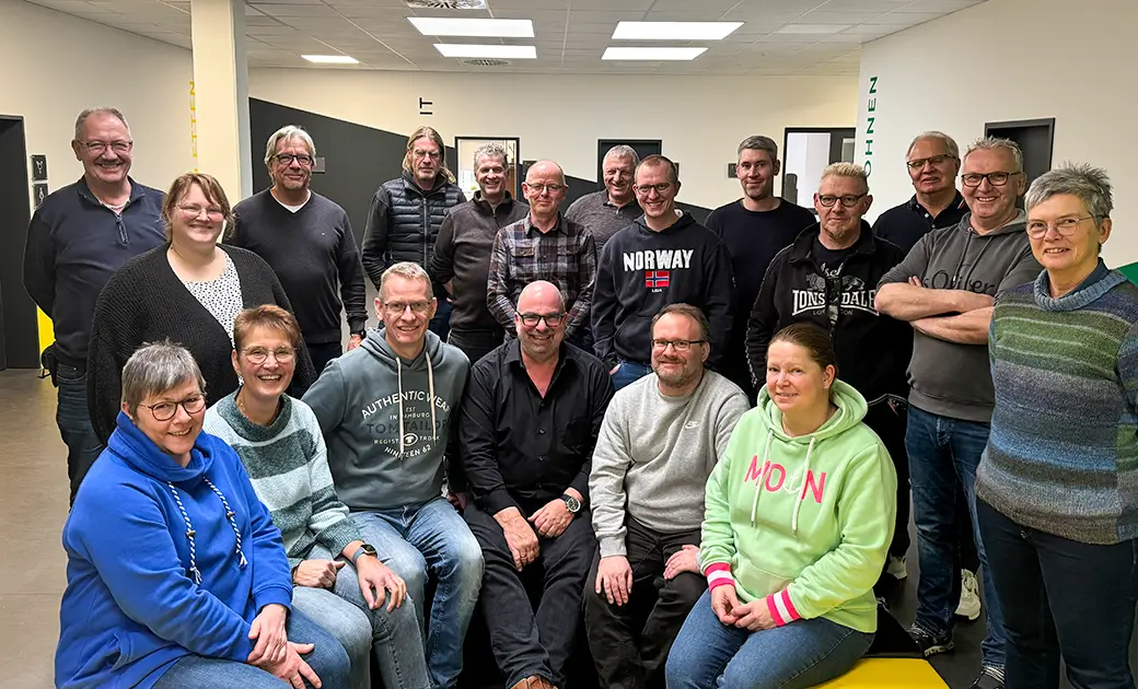 Gruppe von Seminarteilnehmern in einem Raum des Studierendenwerks, einige sitzen auf gelben Sitzbänken, andere stehen dahinter, alle blicken zur Kamera.
