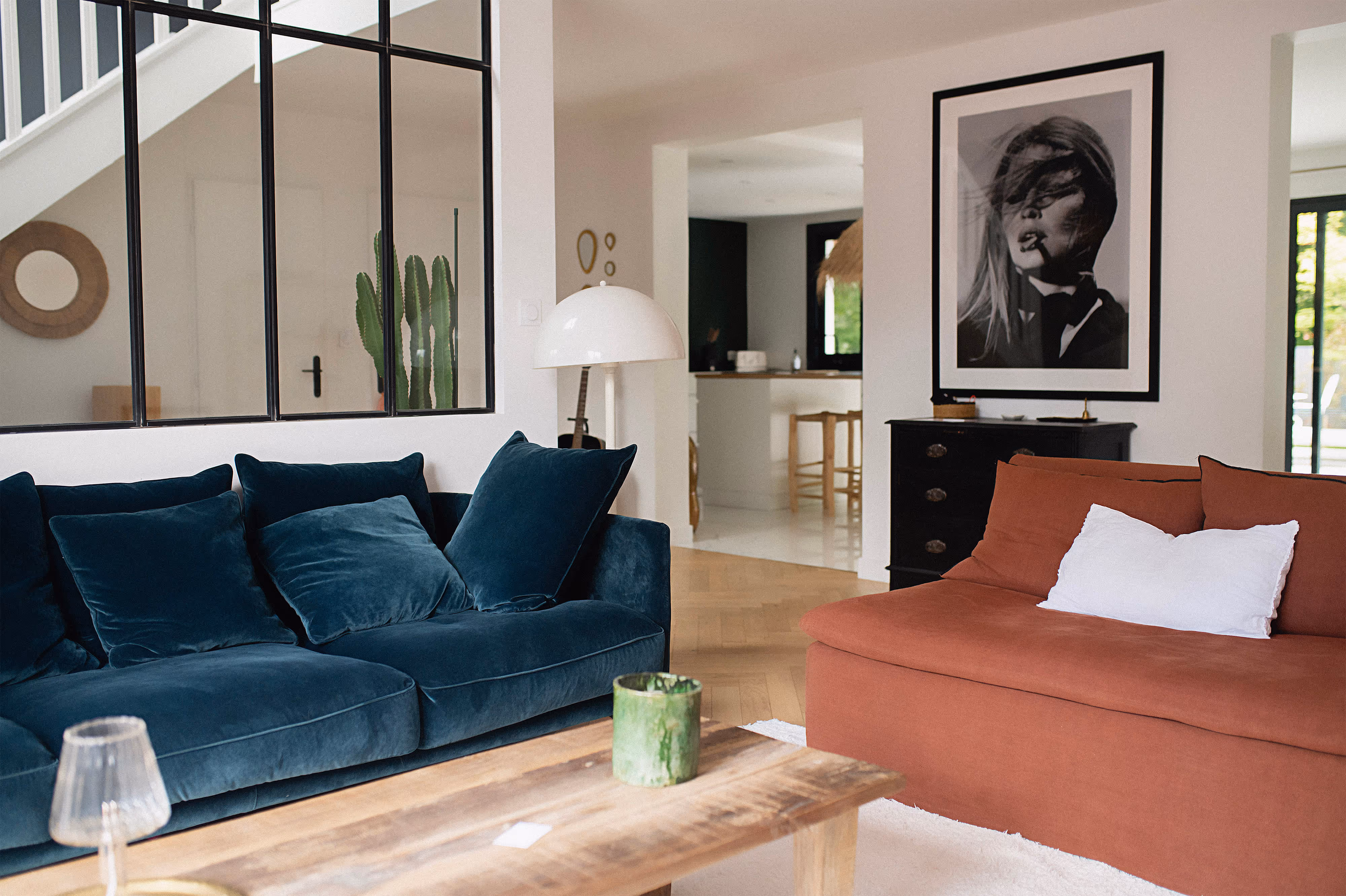 Un salon moderne et convivial avec un canapé en velours bleu foncé et un canapé couleur terracota. 