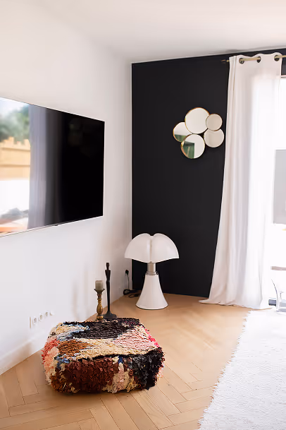 Un salon moderne comprenant un téléviseur à écran plat et un grand miroir réfléchissant.